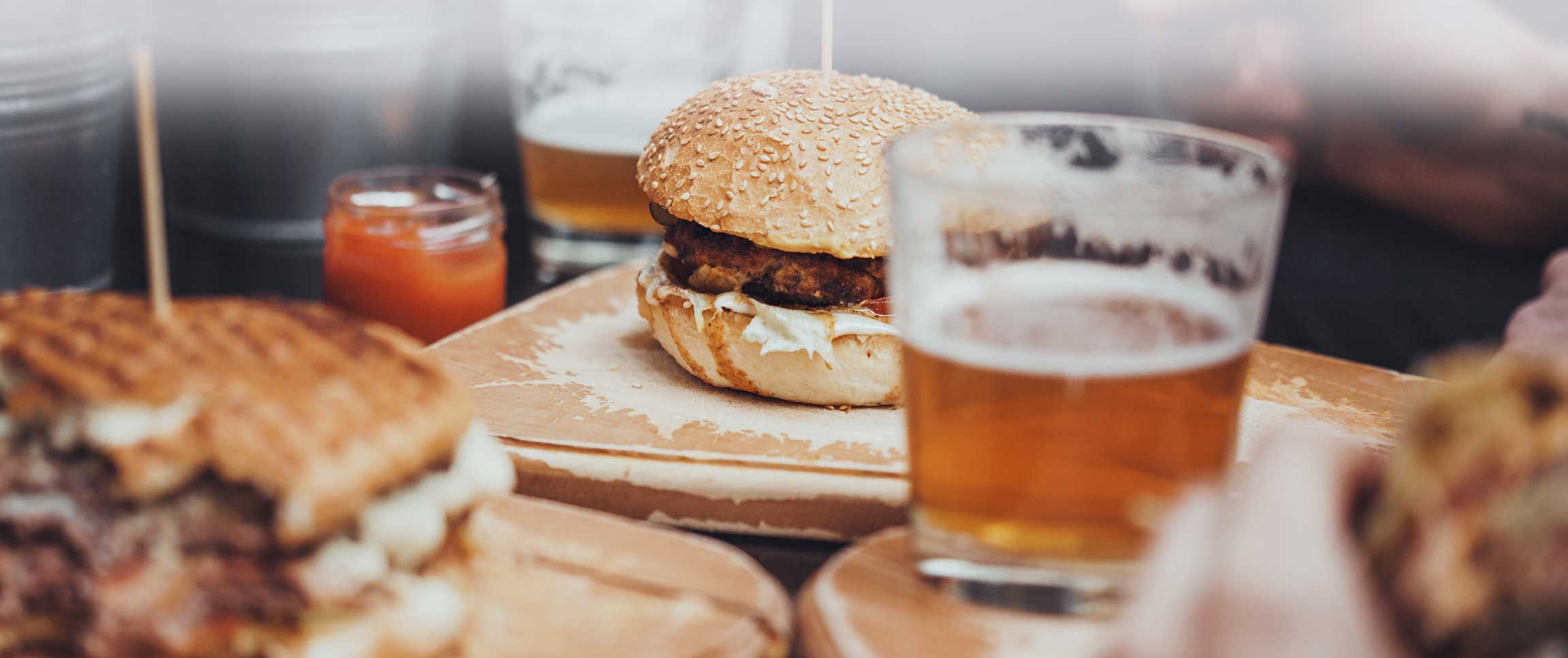 Delicious Pub Food. Burgers And Glasses Of Beer On Wooden Plates