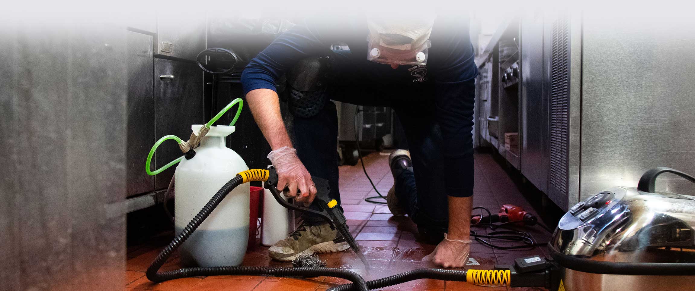 DMS Sanitation Worker spraying fruit fly killer into floor drain