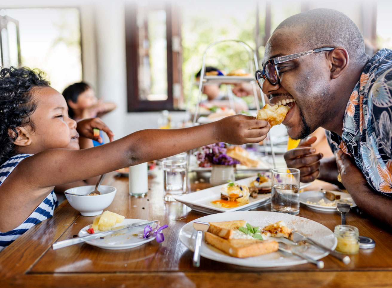 Kid feeding her dad a bite of food
