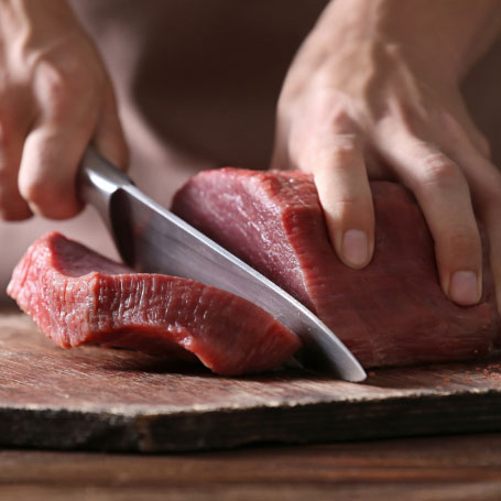 Butcher Slicing a Fresh Slab of Beef
